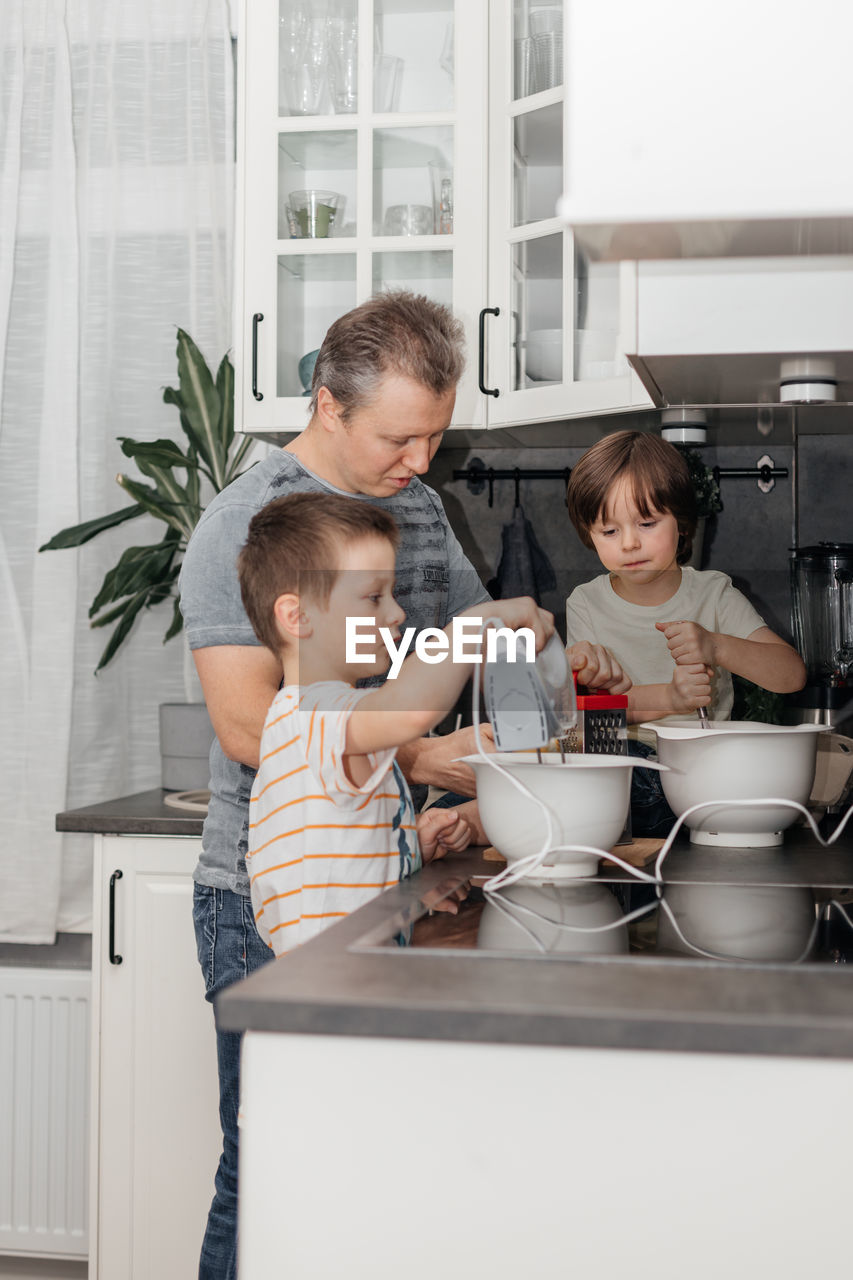 Dad and sons knead and prepare dough for baking muffins or biscuits. dad helps and teaches children