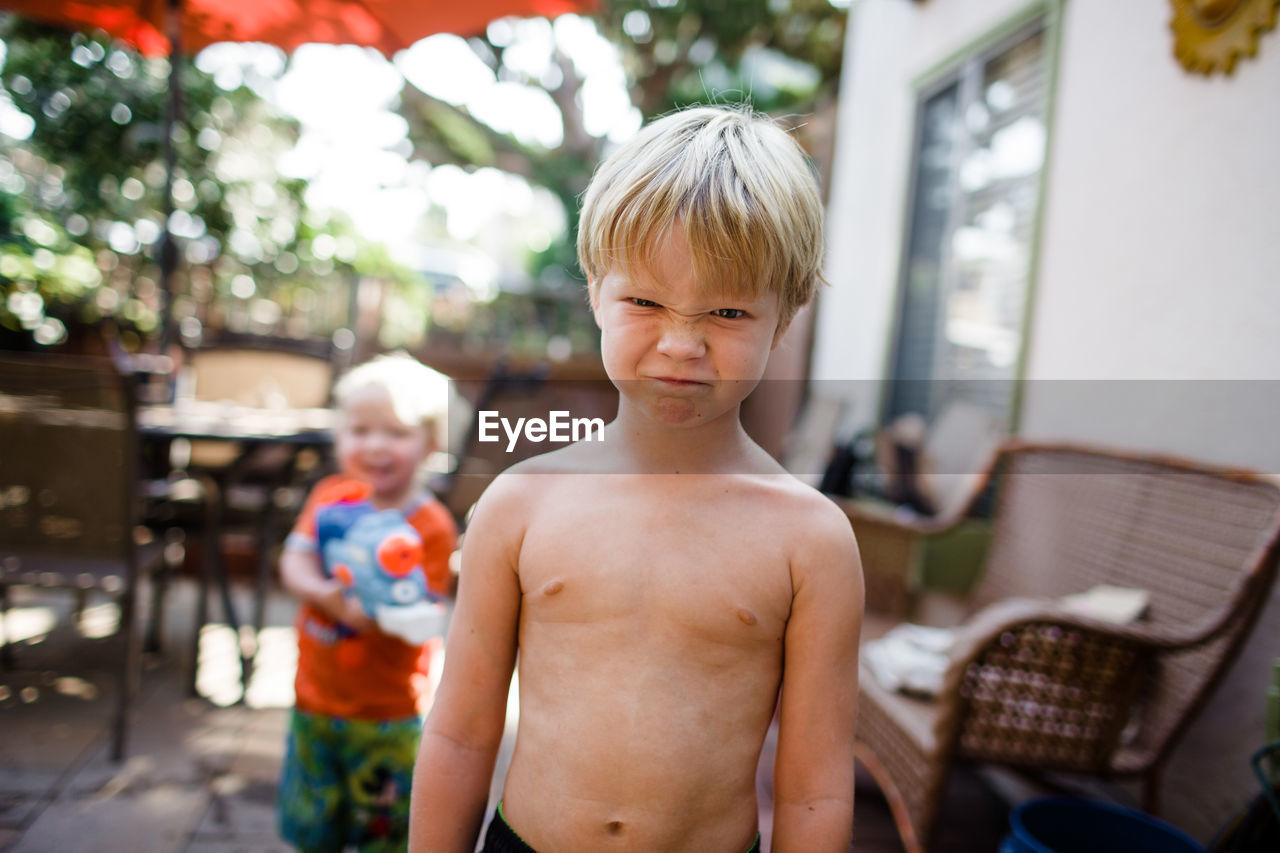 Older brother making funny face with younger brother in background