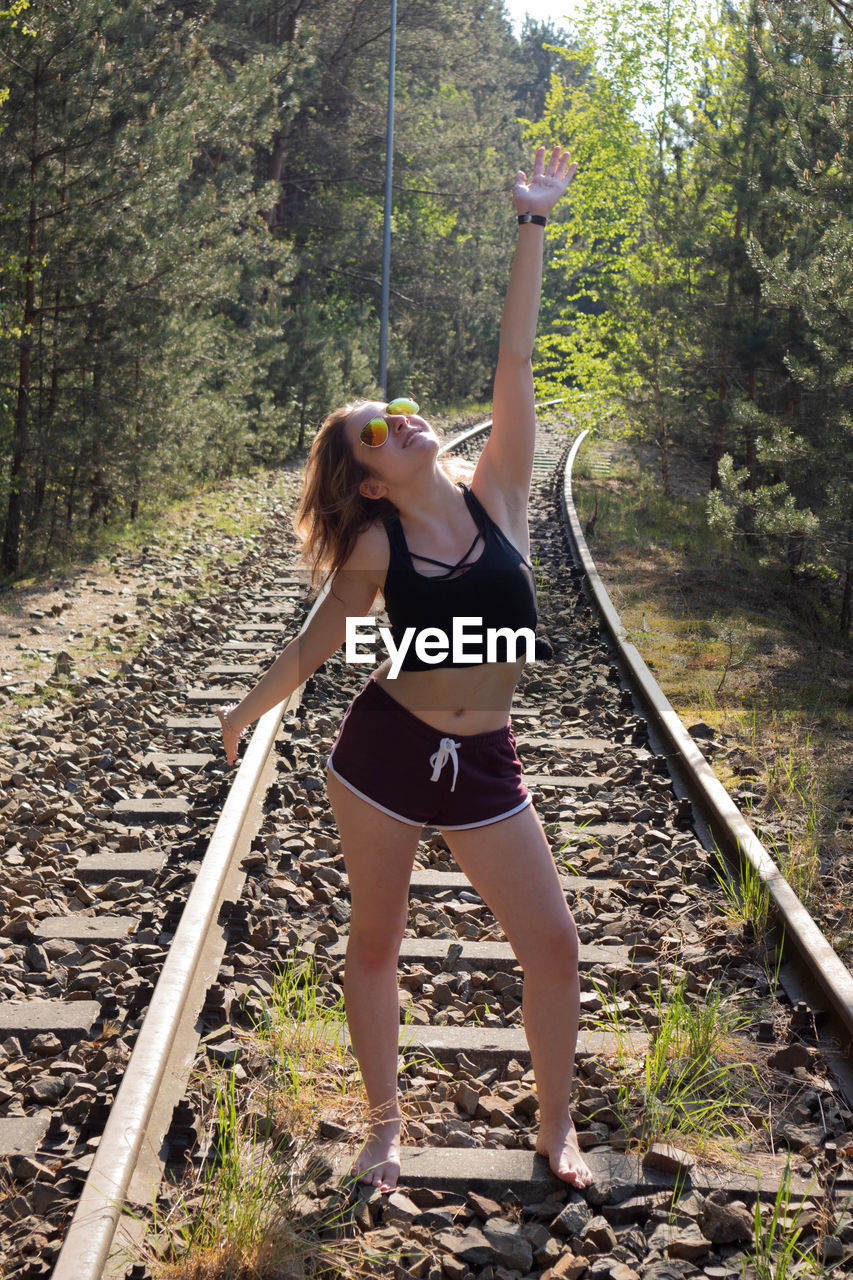 Full length of young woman standing on railroad track