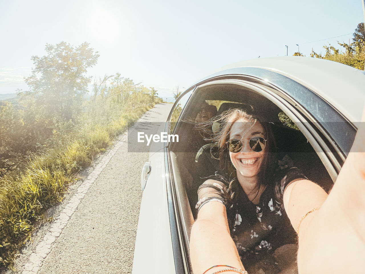 Portrait of smiling woman doing selfie while sitting in car