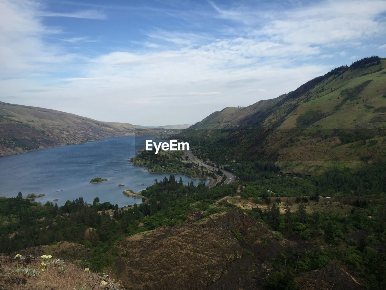 High angle view of river by mountain against cloudy sky