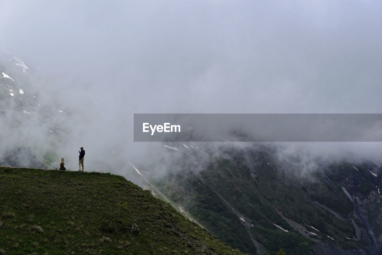 People standing on mountain against sky