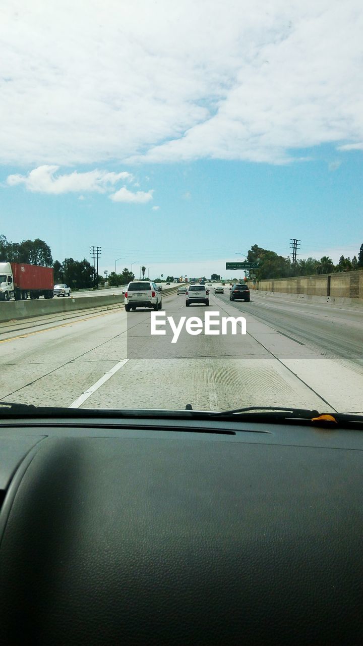 VEHICLES ON ROAD AGAINST SKY