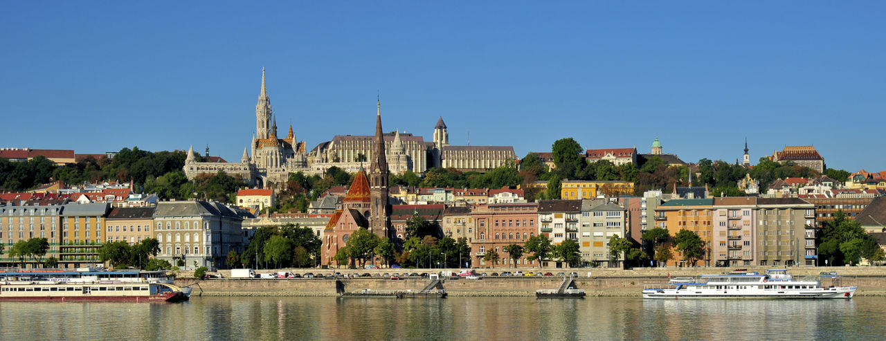 Panoramic view of buildings in city against clear blue sky