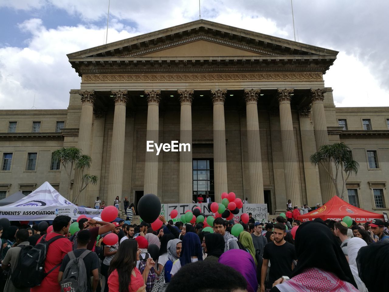 CROWD IN FRONT OF BUILDING AGAINST SKY