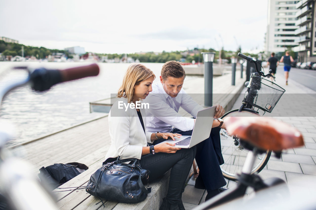 Business people working on laptop against clear sky