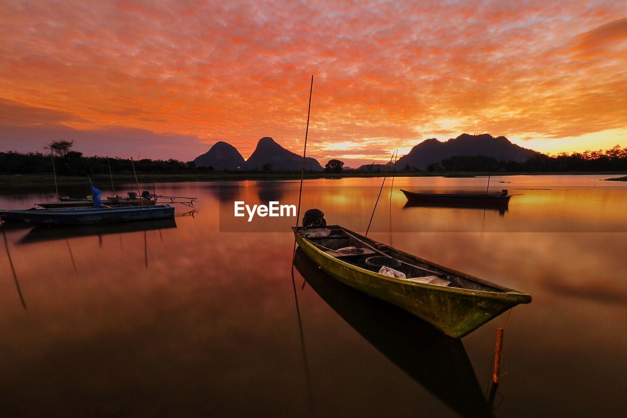 Sailboats moored on lake against sky during sunset