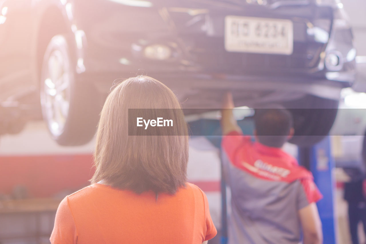 REAR VIEW OF WOMAN STANDING BY BUS