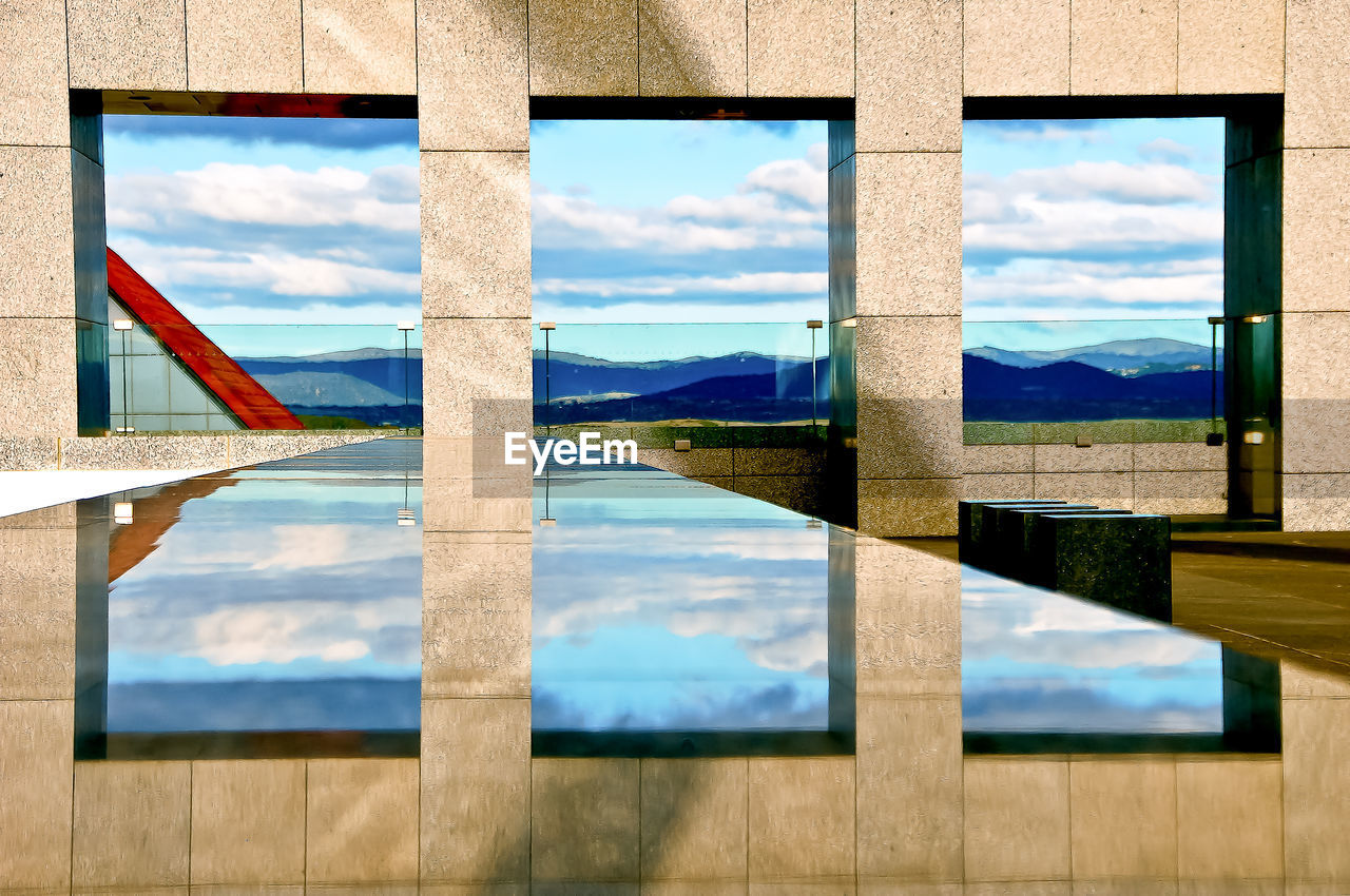 Windows and sky reflecting on marble retaining wall