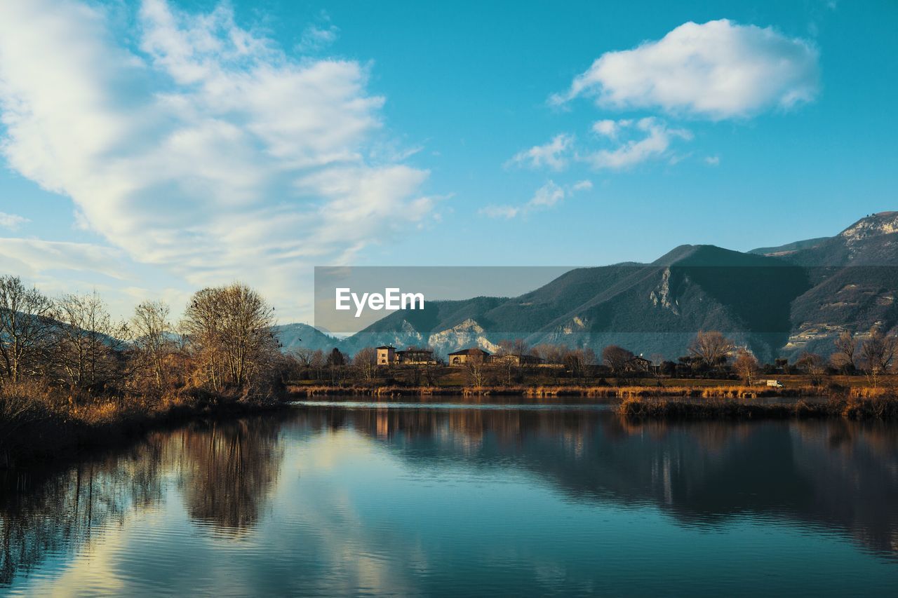 Scenic view of lake against mountains cloudy sky