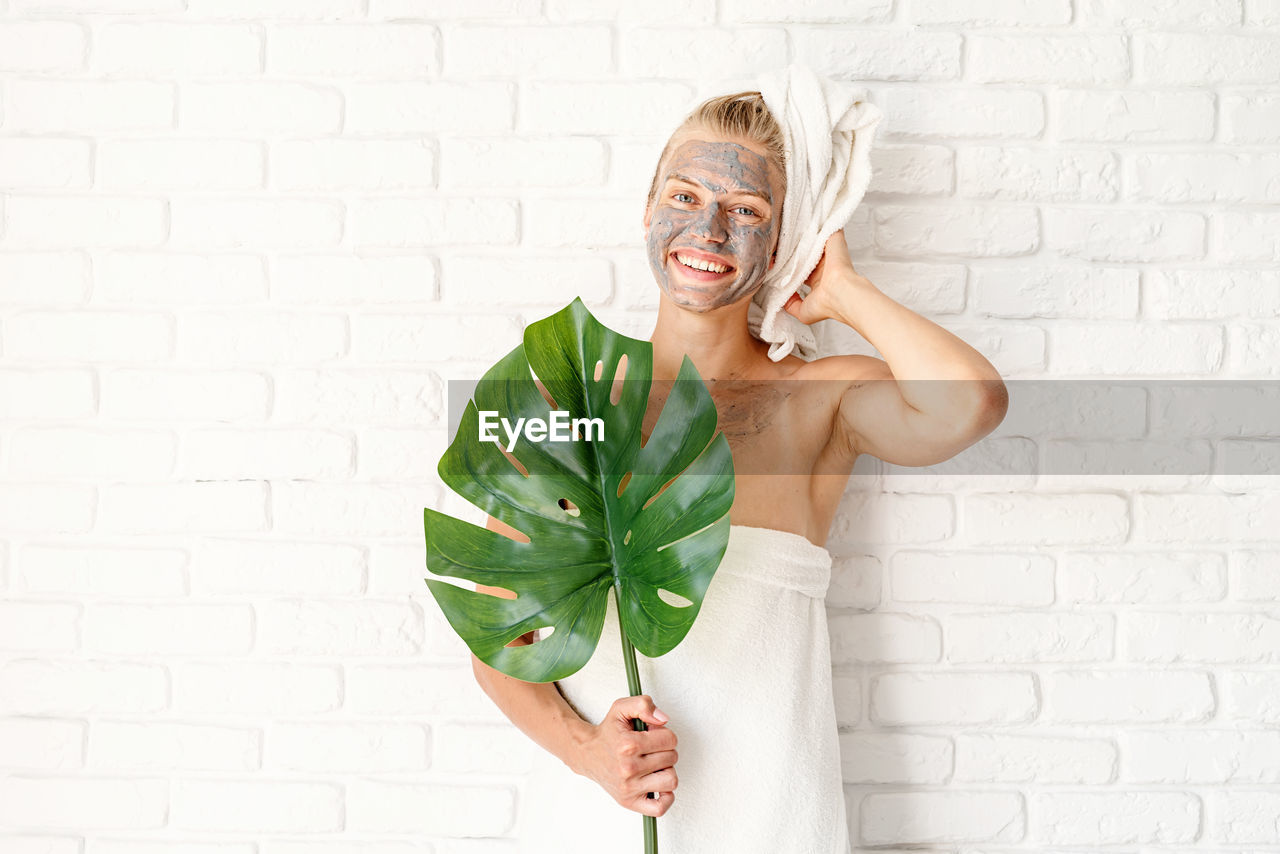  happy smiling woman wearing bath towels with a clay facial mask on her face