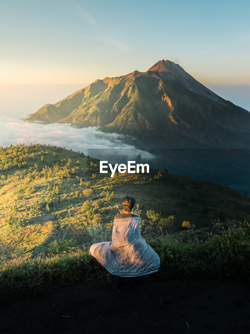 Woman sitting on land against sky