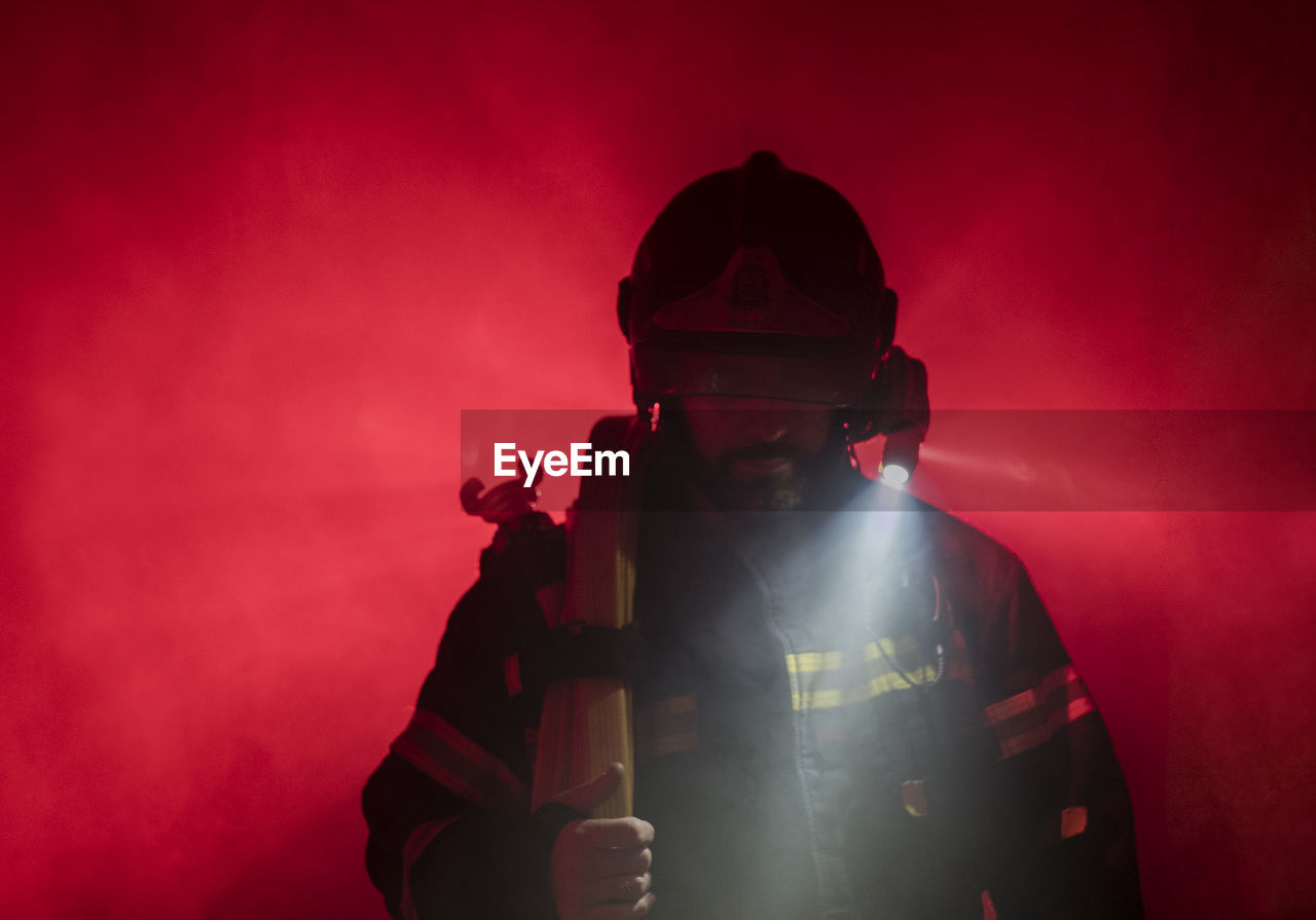 Close-up of firefighter against red light