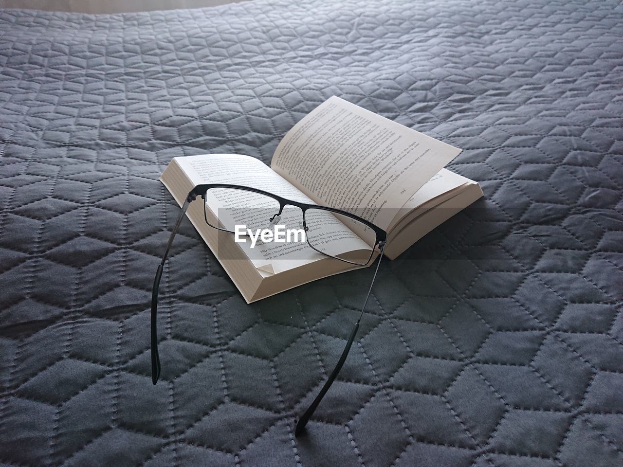 High angle view of open book on bed