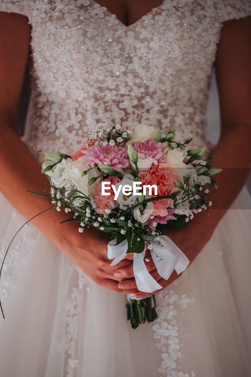 Midsection of bride holding bouquet