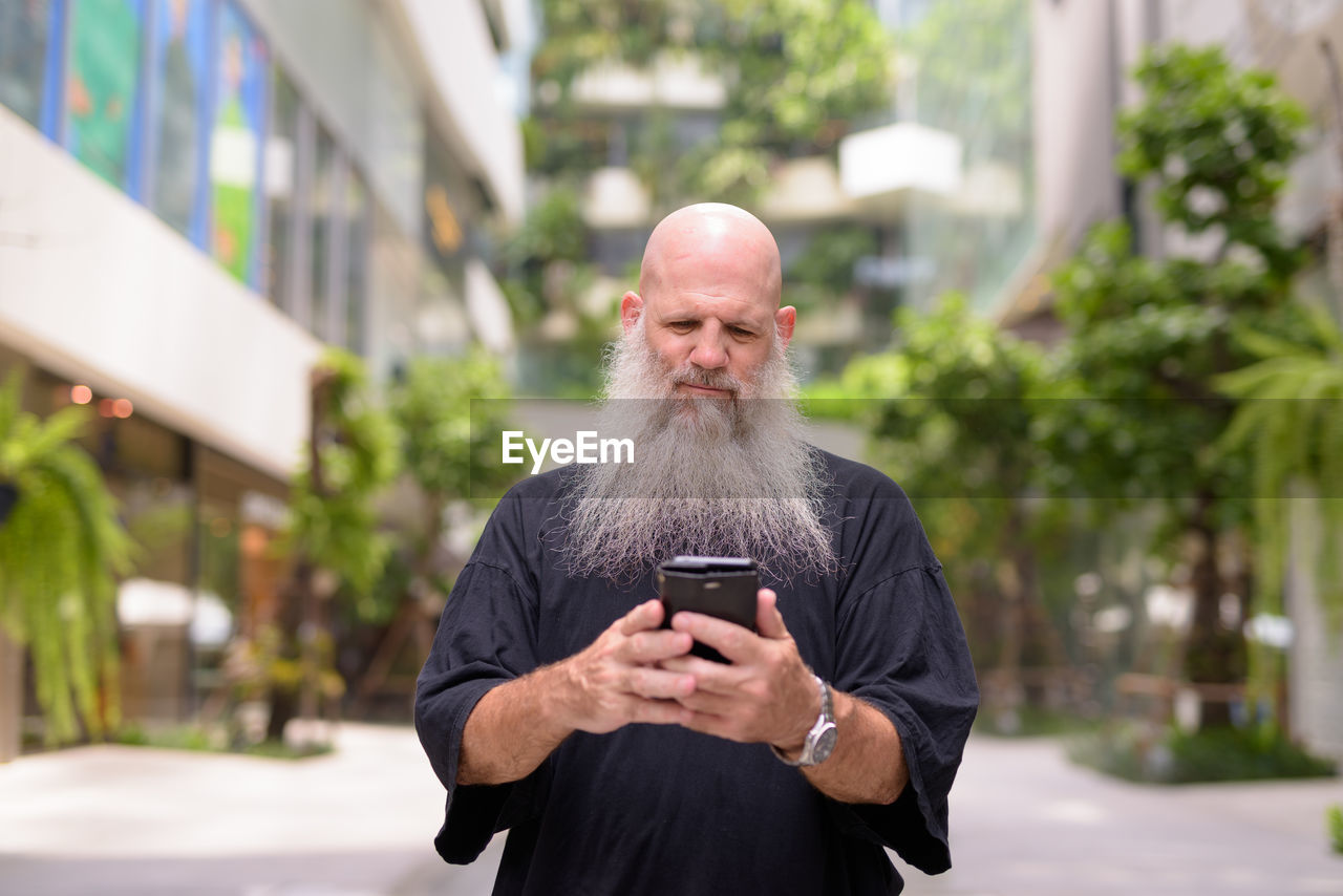 MAN USING PHONE WHILE STANDING ON CITY