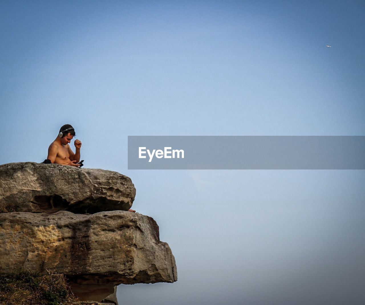 MONKEY SITTING ON ROCK AGAINST SKY