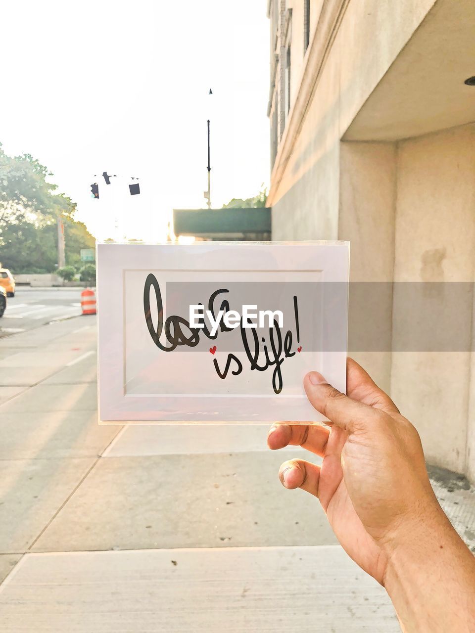 Midsection of person holding text against wall in city