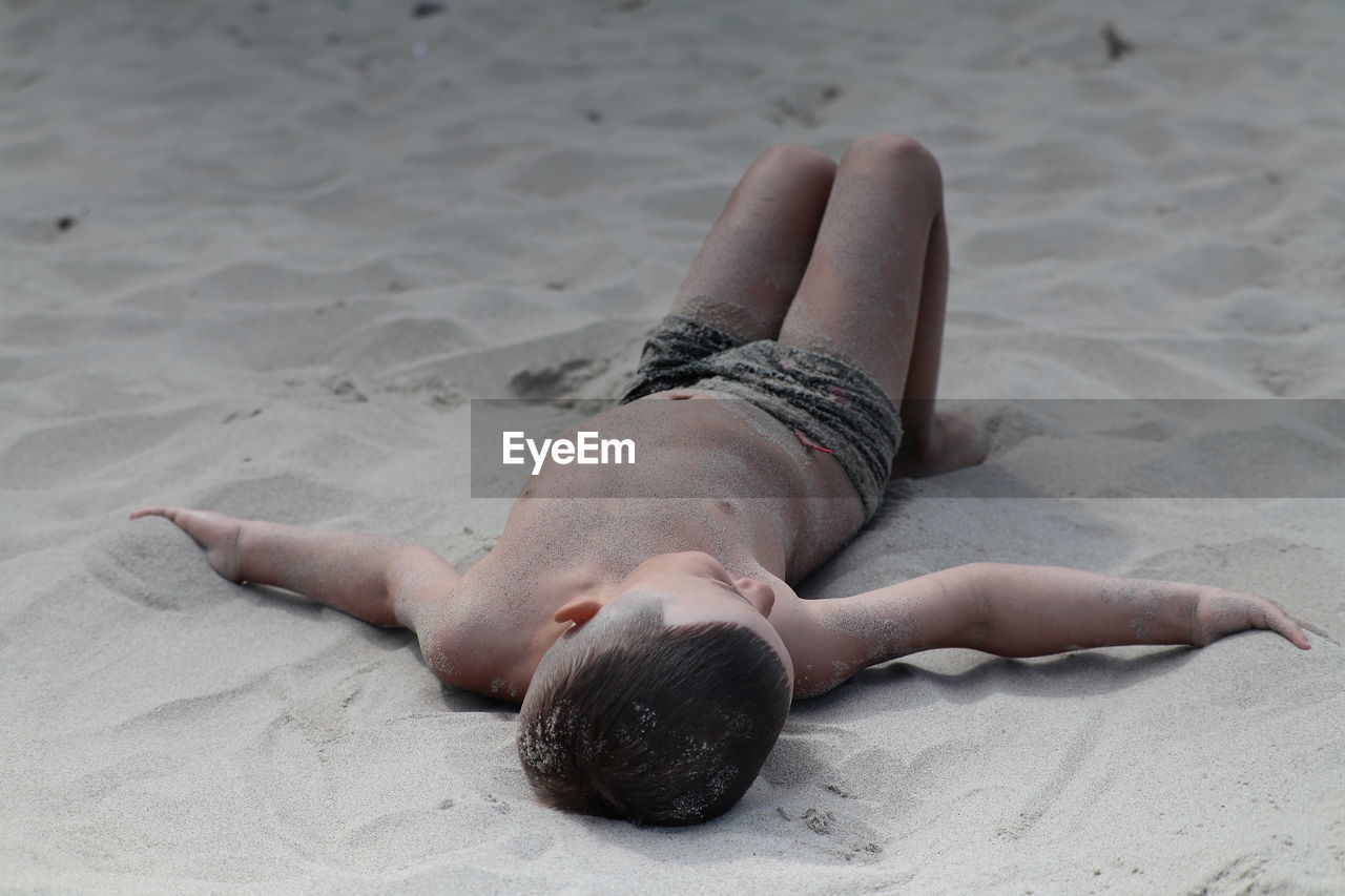 low section of woman sitting on sand at beach