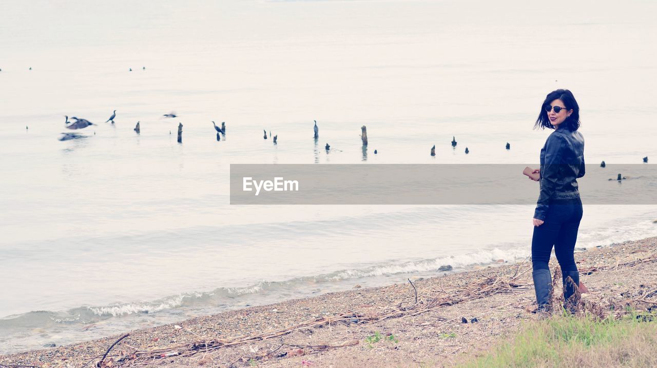 Full length of woman standing at beach during winter