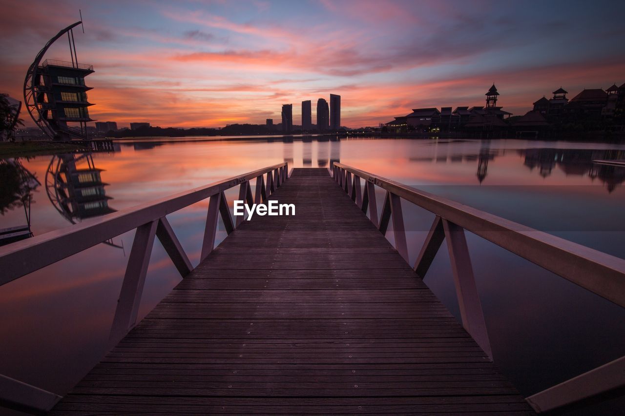 Pier over lake against sky during sunset