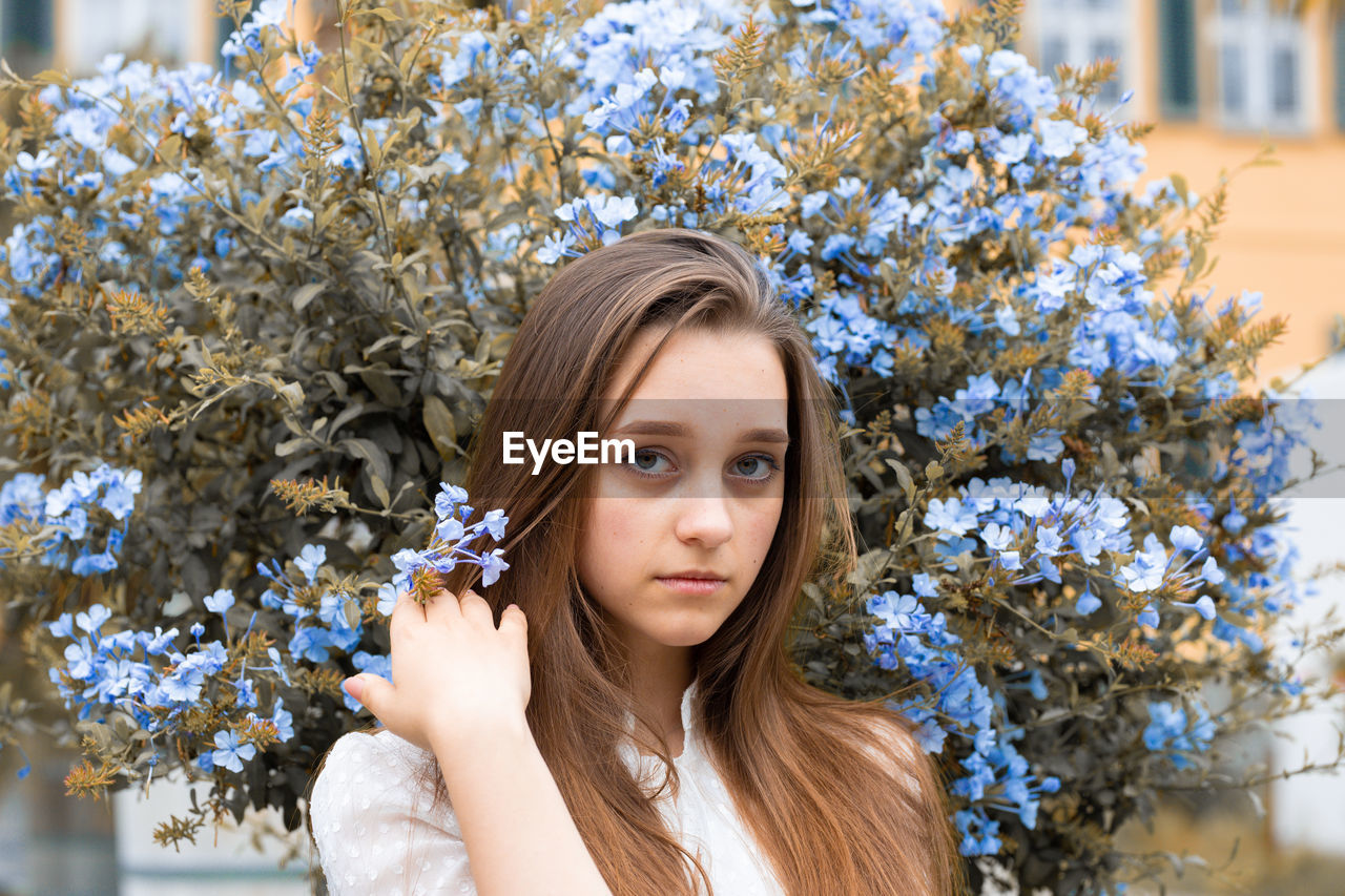 Portrait of beautiful woman against white flowering plants