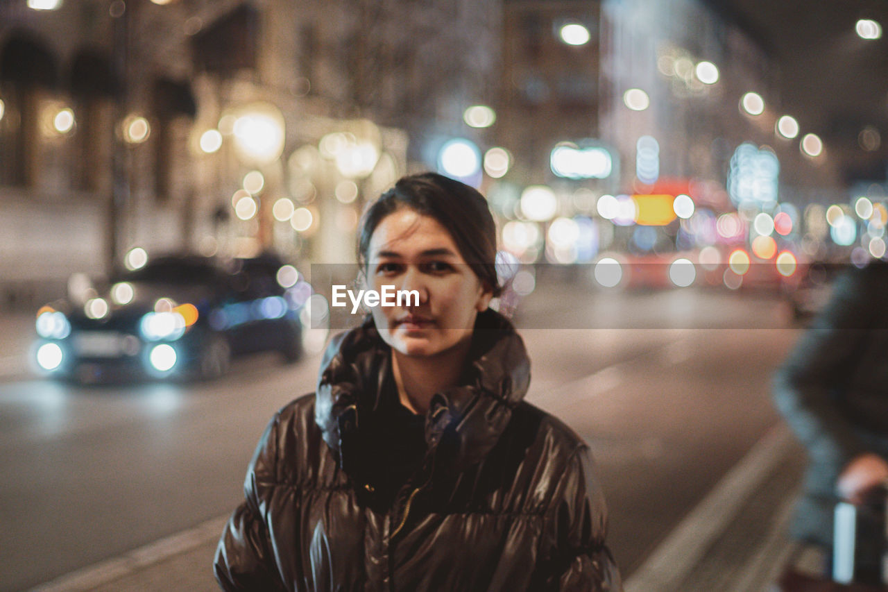 Portrait of man standing on city street at night