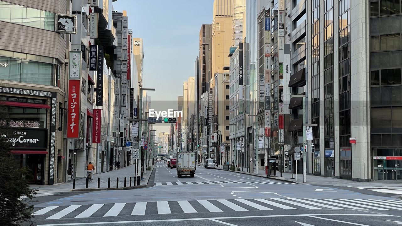 architecture, city, road, lane, street, building exterior, built structure, urban area, transportation, sign, neighbourhood, road marking, city street, downtown, infrastructure, cityscape, metropolitan area, building, marking, symbol, crosswalk, city life, motor vehicle, zebra crossing, mode of transportation, car, day, crossing, metropolis, sky, travel destinations, residential district, town, nature, the way forward, skyscraper, outdoors, residential area, office building exterior, road sign, travel, pedestrian crossing, communication, diminishing perspective, no people