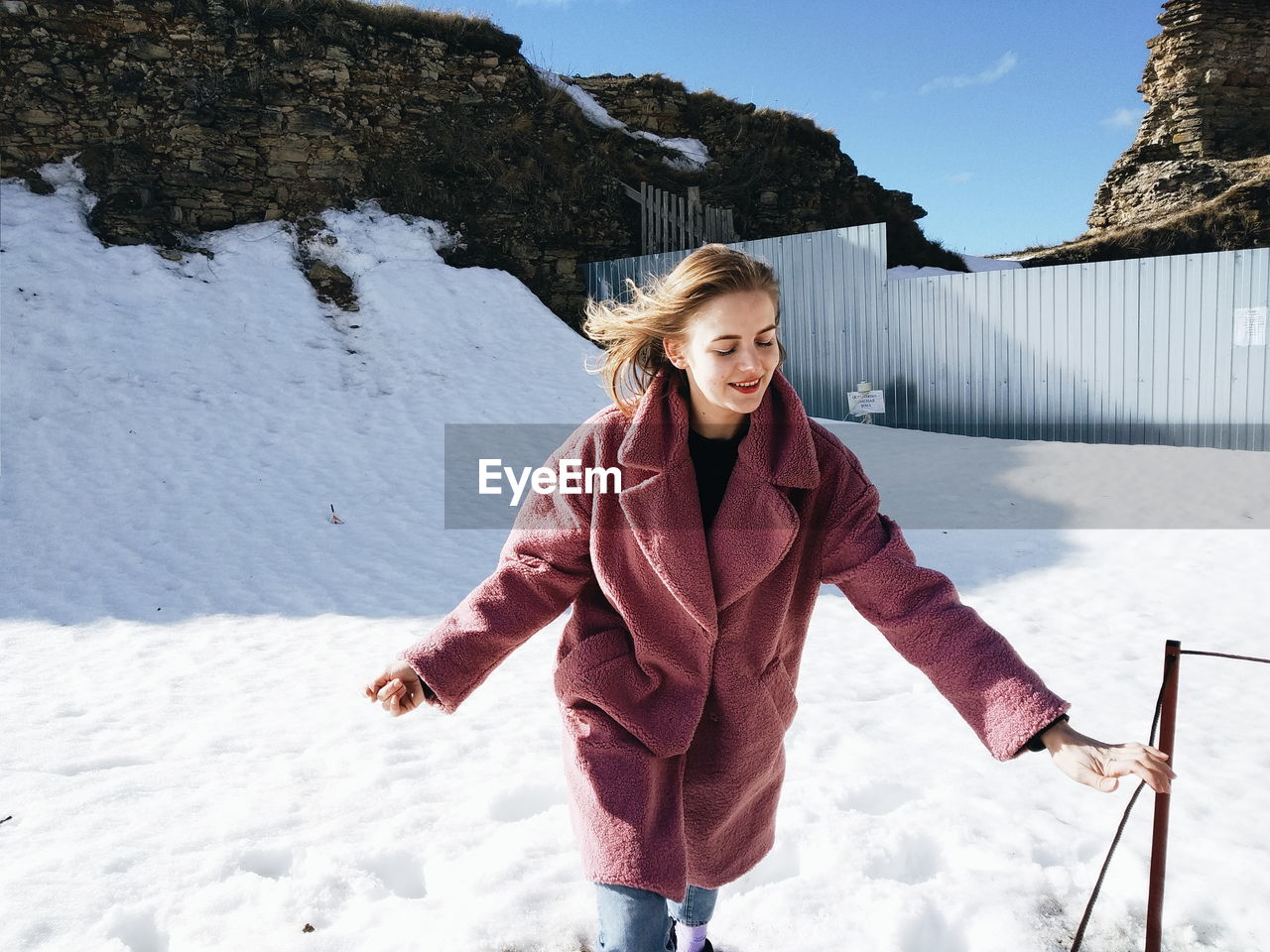 Smiling young woman standing on snowy field