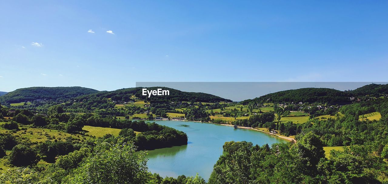 Scenic view of lake and mountains against blue sky