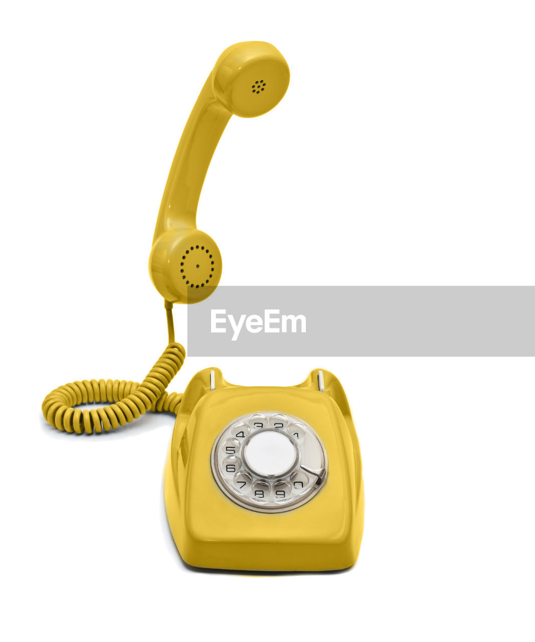 Yellow rotary phone against white background