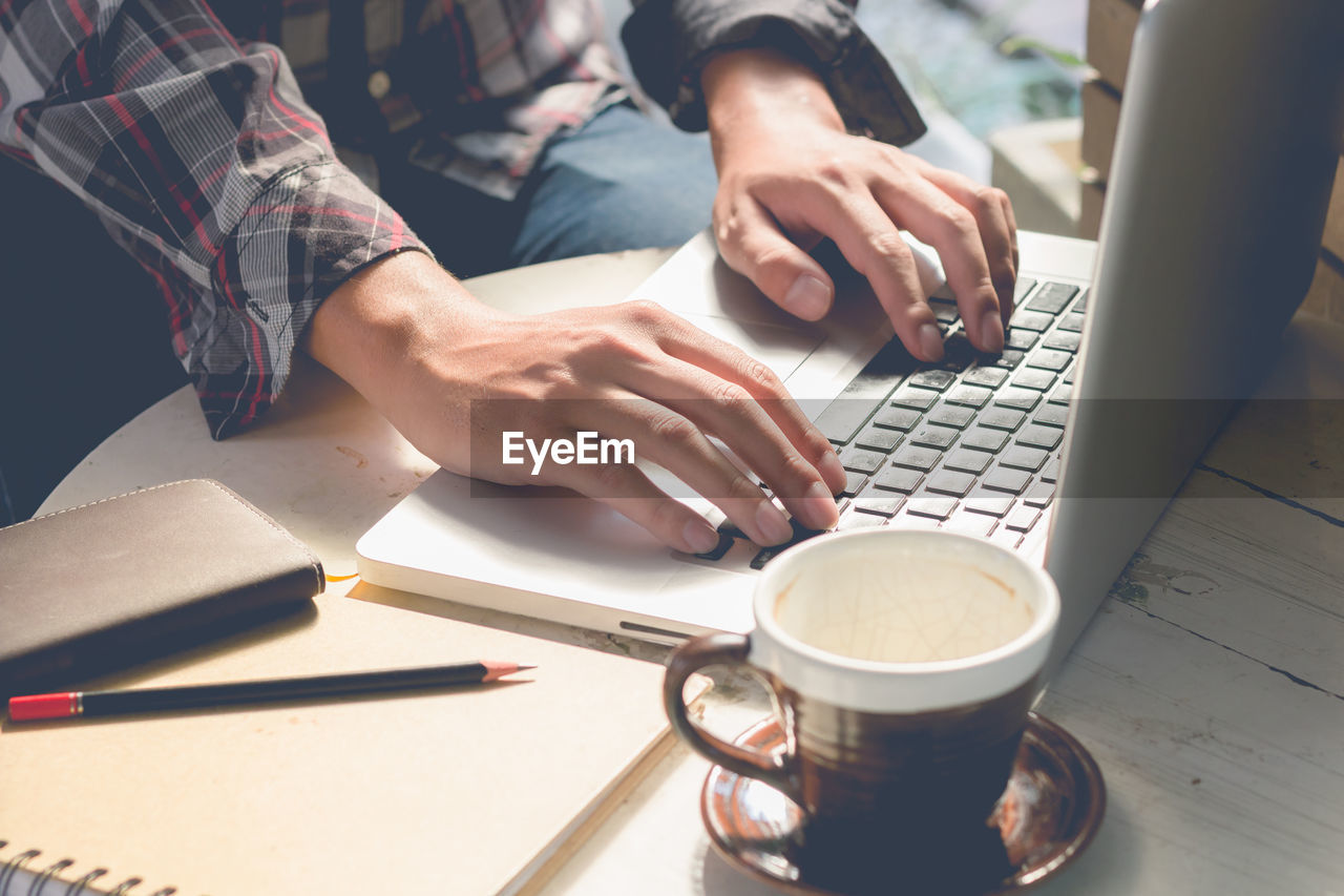 Midsection of woman using laptop at table