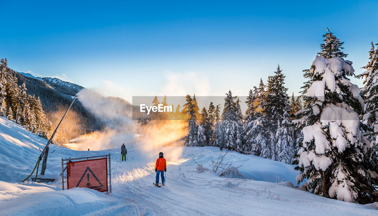 PEOPLE ON SNOW COVERED LAND AGAINST SKY