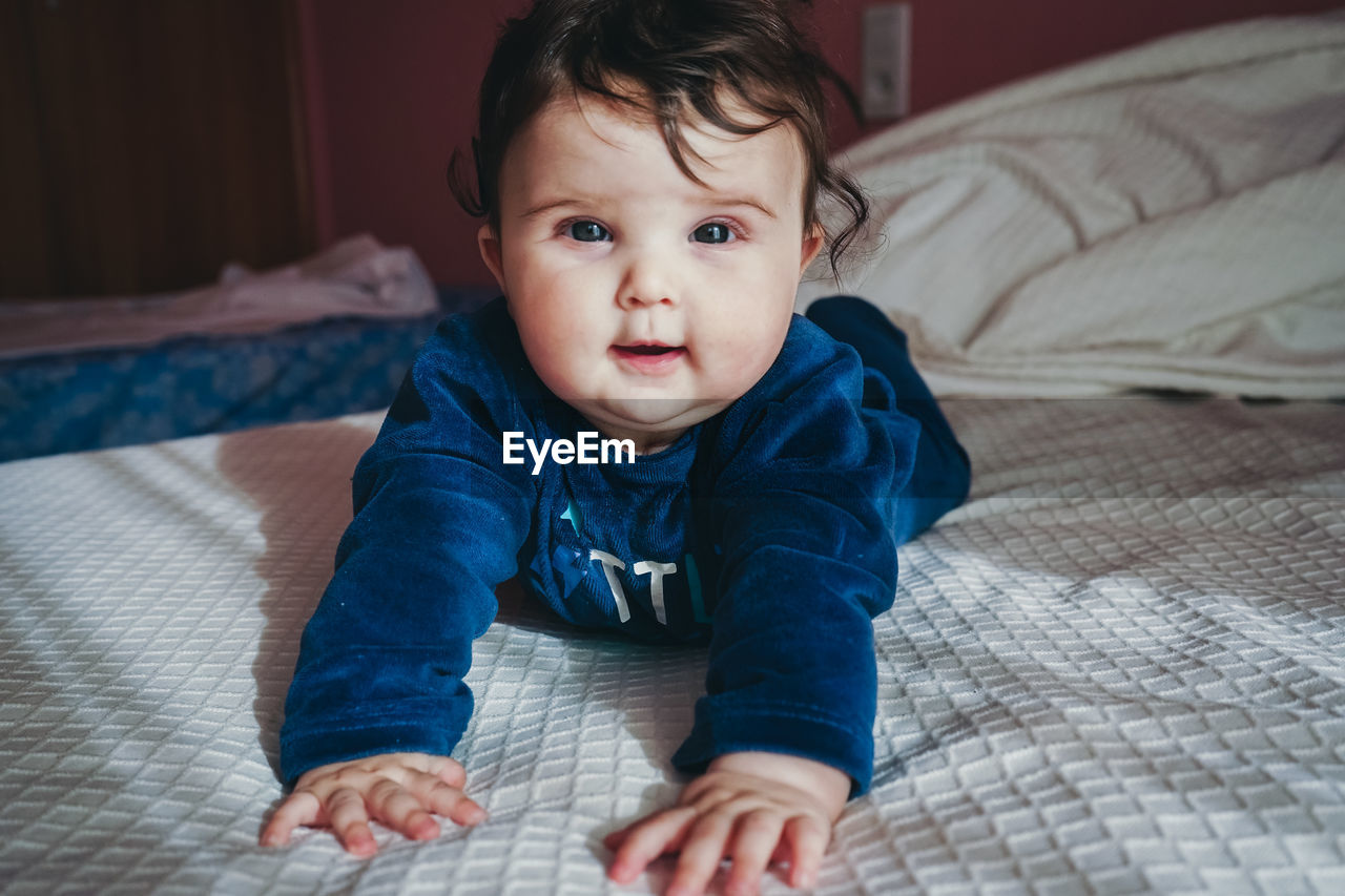 Portrait of cute baby girl on bed at home