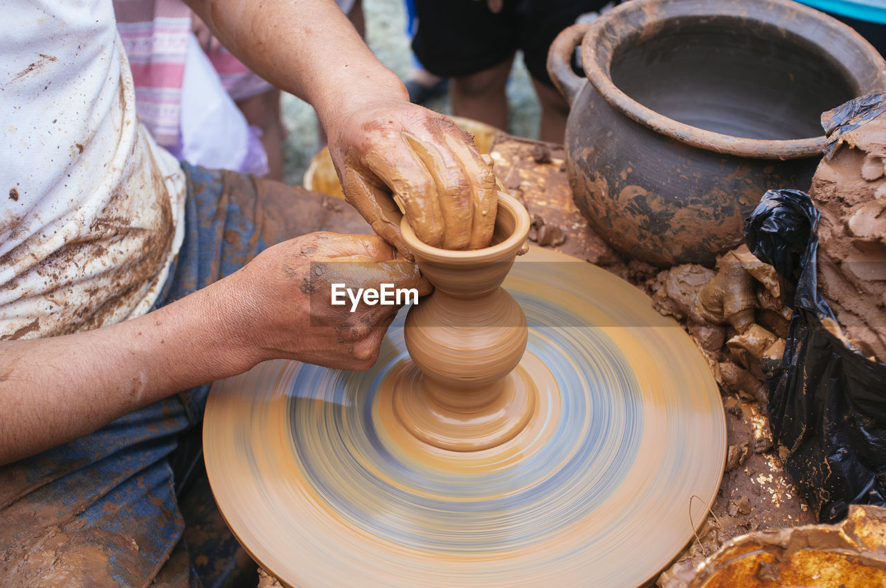 Close-up of man shaping pottery clay on wheel