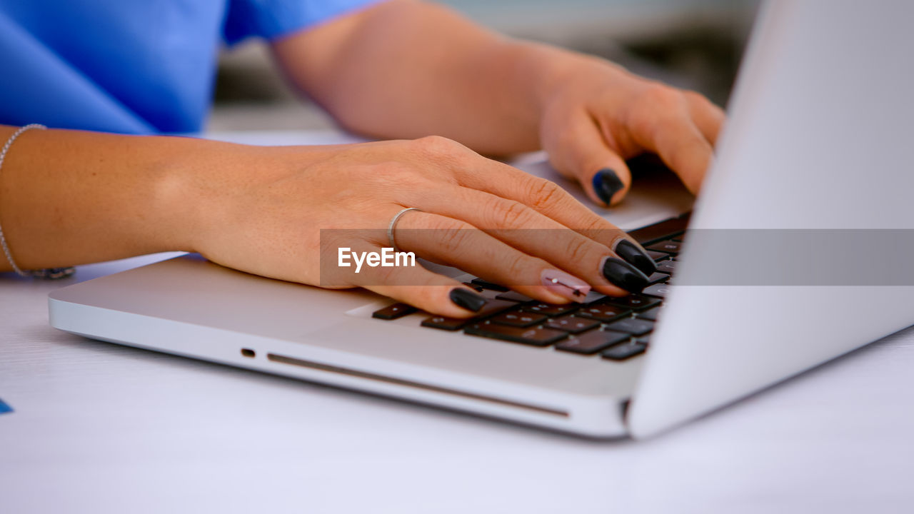 Cropped hands of businesswoman using laptop at home