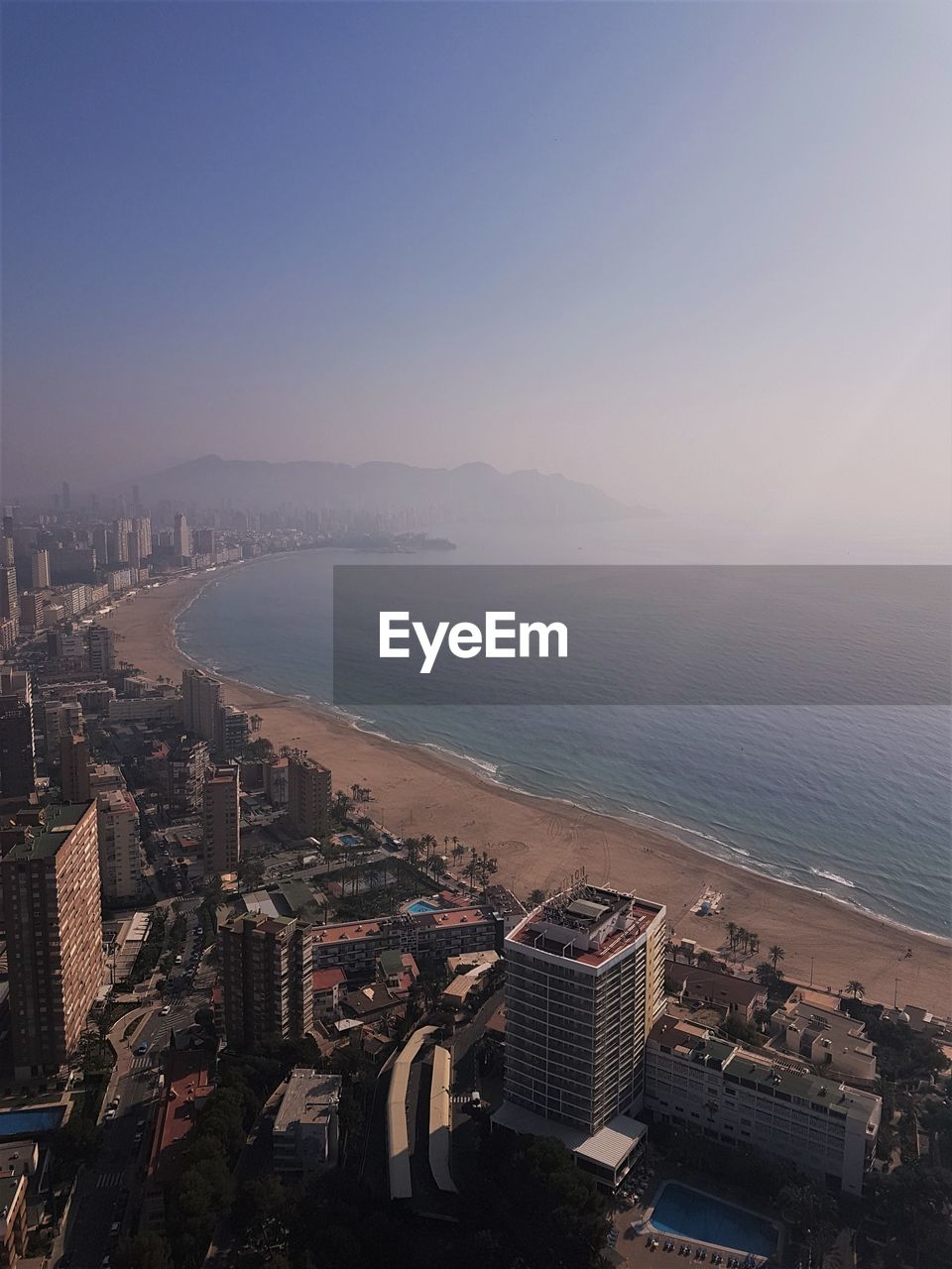 High angle view of cityscape by sea against clear sky