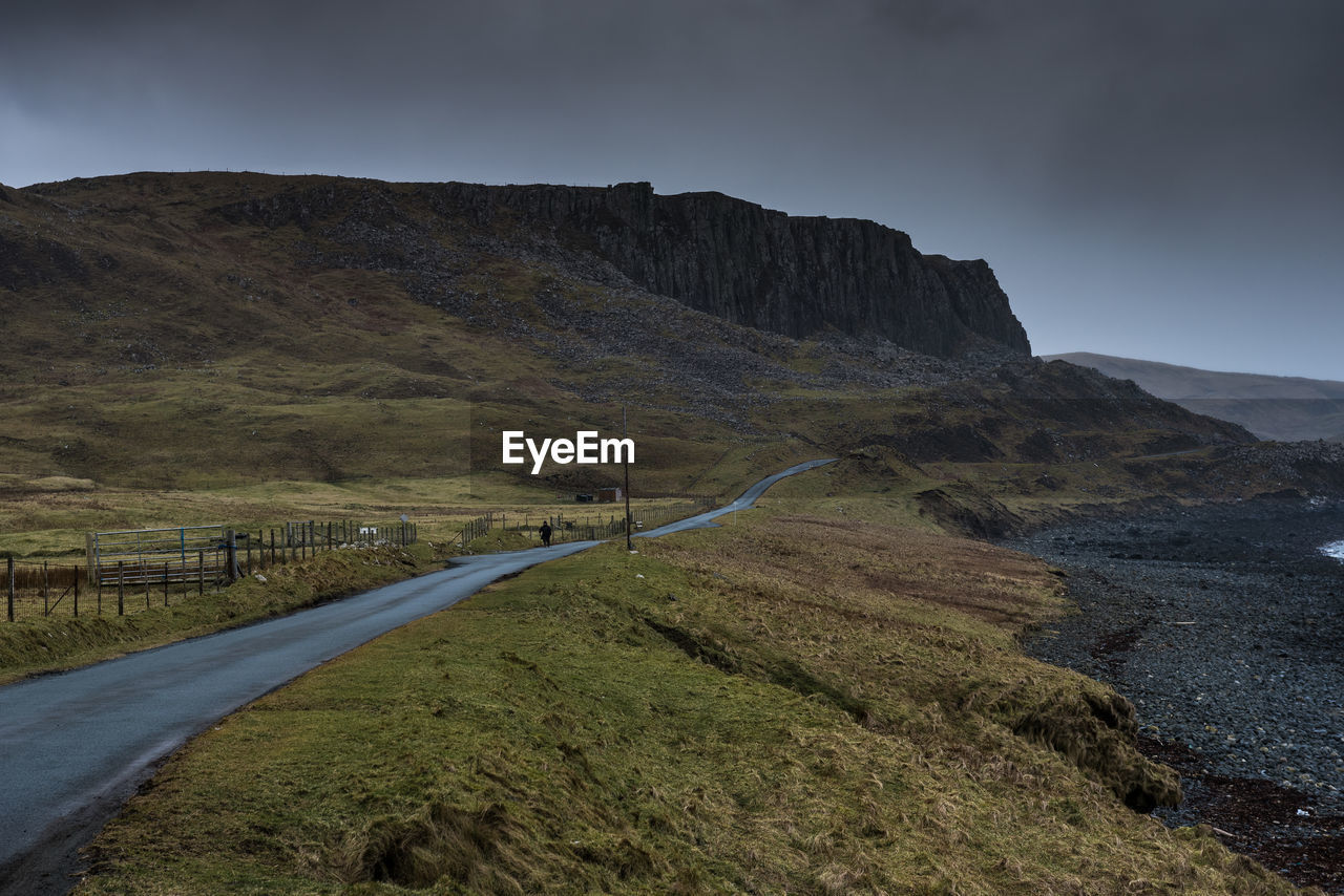 Road leading towards mountains against sky