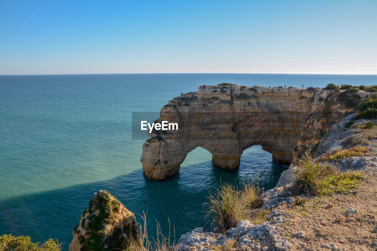 Scenic view of rock formation in sea against clear sky