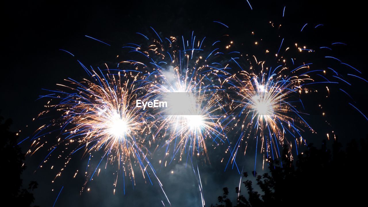 LOW ANGLE VIEW OF FIREWORKS AT NIGHT