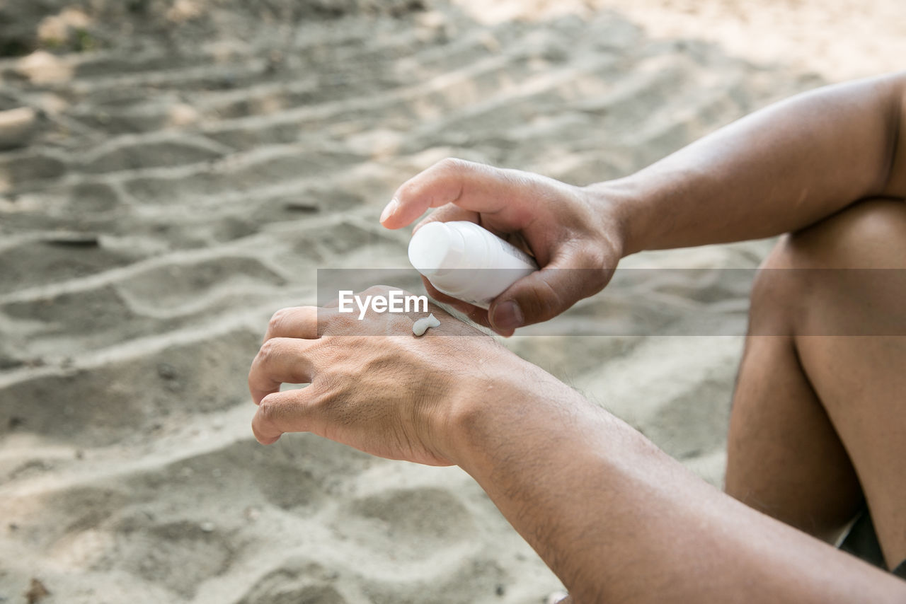 Close-up of man applying moisturizer on hand