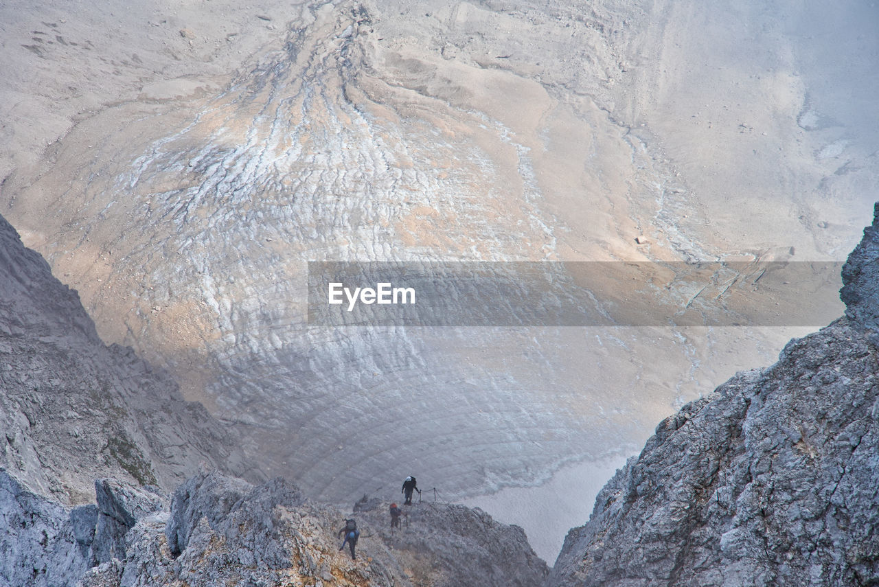 REAR VIEW OF MAN WALKING ON ROCK