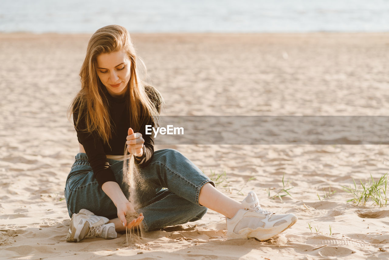 Smiling young woman sitting on beach