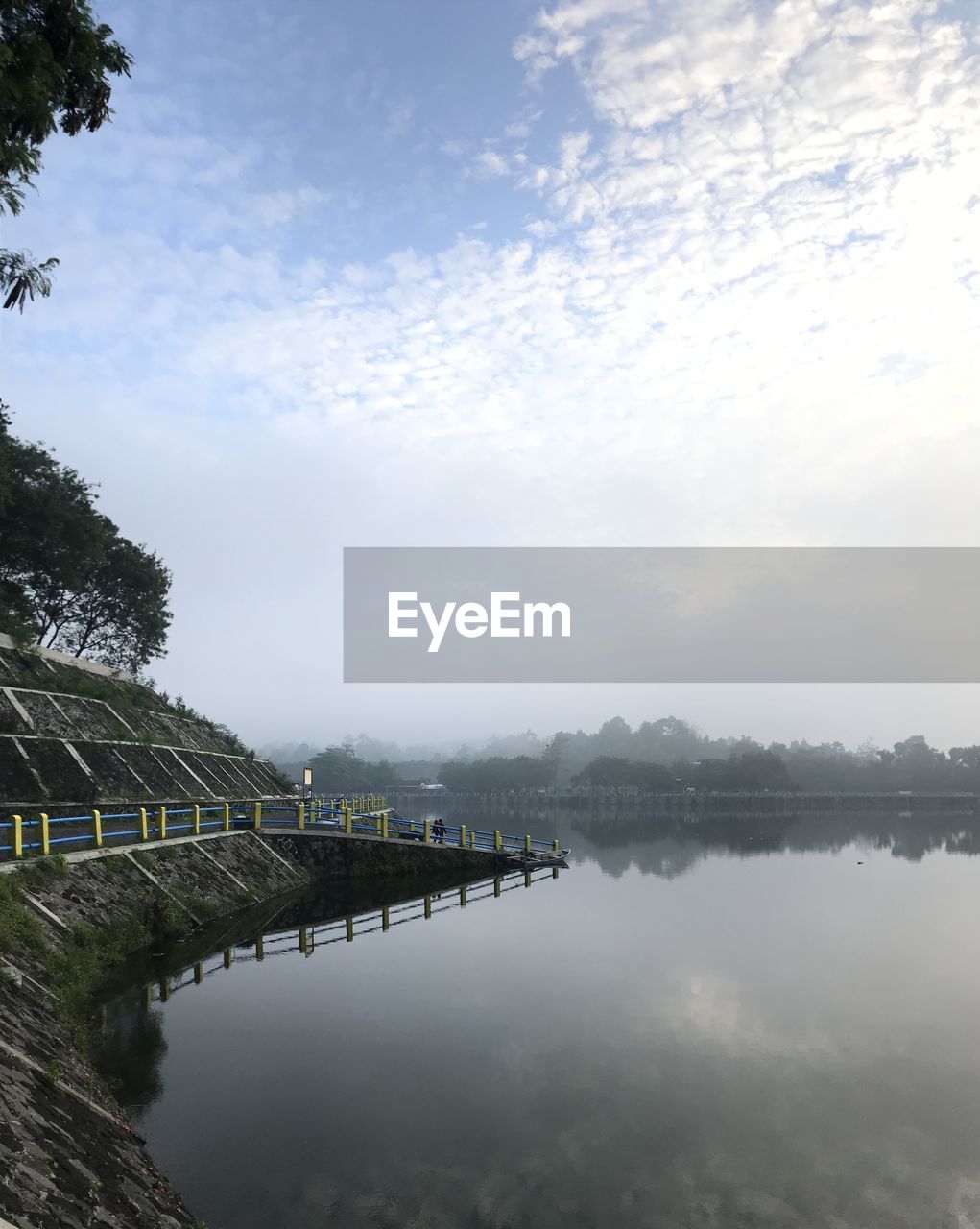 REFLECTION OF TREES IN LAKE AGAINST SKY