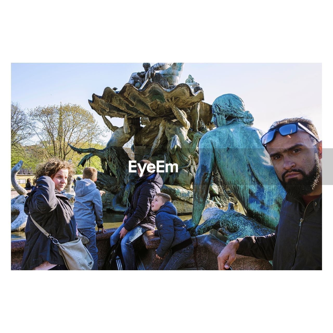 PEOPLE BY STATUE AGAINST CLEAR SKY