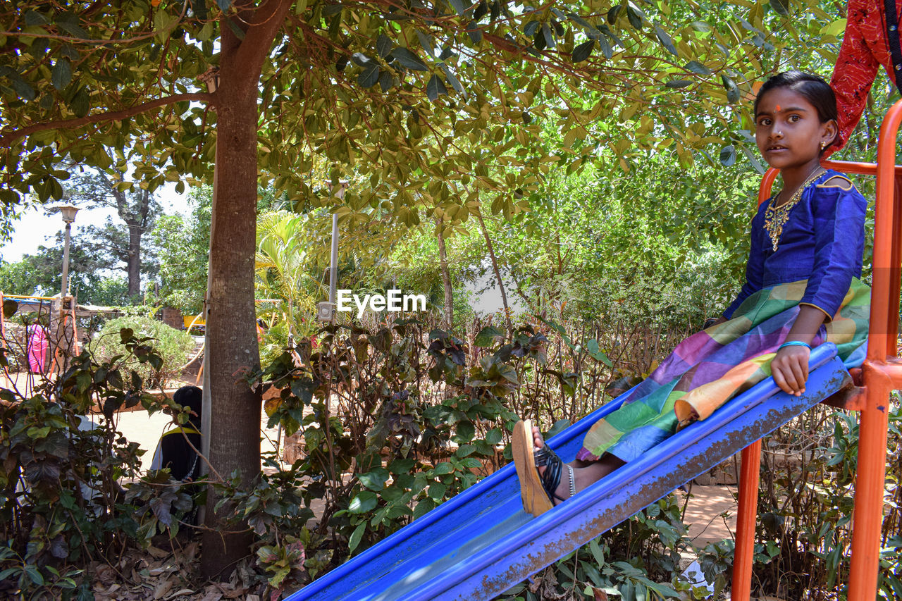 Portrait of girl sitting on slide at park