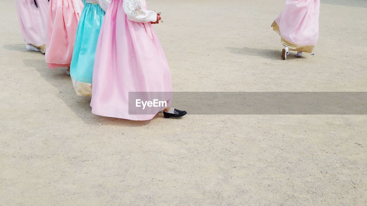 Low section of women in costume walking on sand