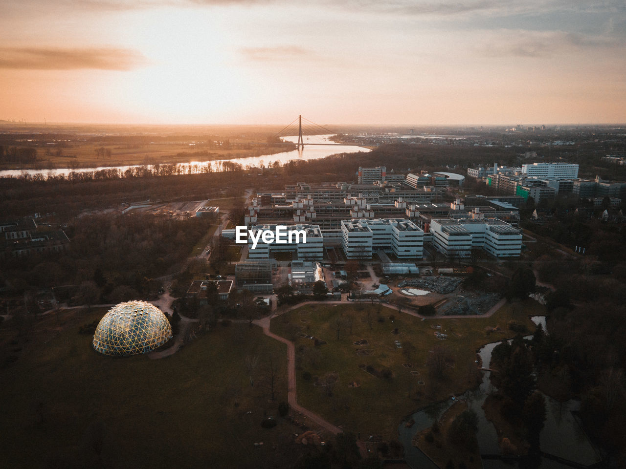 High angle shot of townscape against sky at sunset with a dome greenhouse