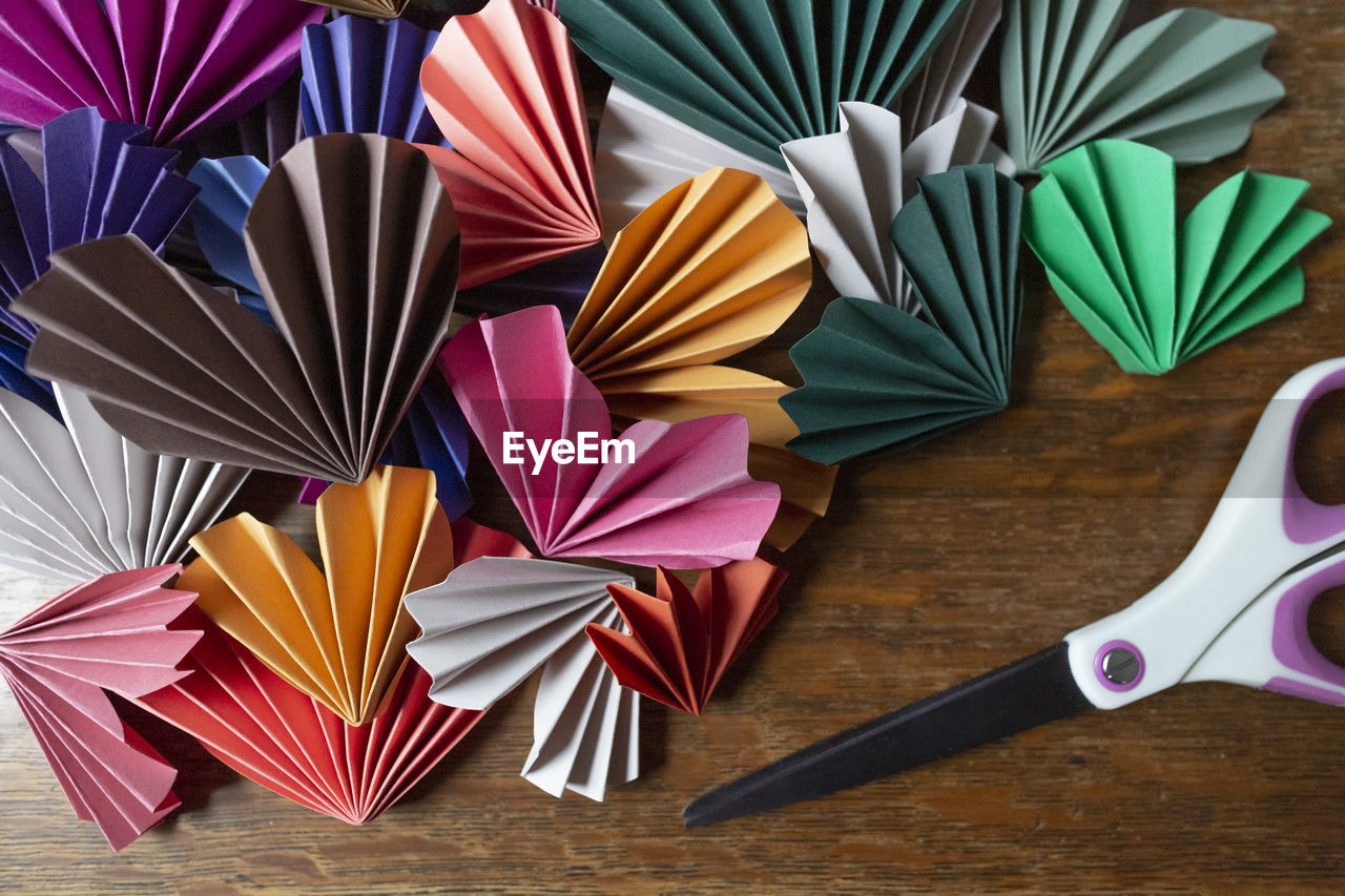 Valentine paper origami hearts cut out and folded next to scissors