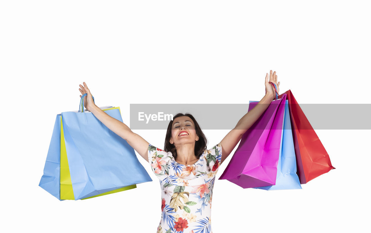 Smiling woman holding colorful shopping bags against white background